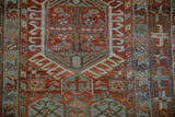 Close-up of a vintage Karaja rug's geometric medallion with hook and latch motifs in rust and blue.
