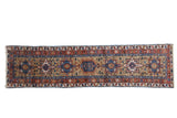 Vintage Karaja rug runner with a column of geometric medallions in ochre, terracotta red, and sapphire blue.