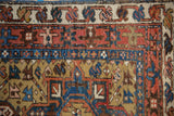 Complex geometric borders in ochre, blue, and terracotta on a vintage hand-knotted Karaja rug.