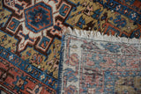 Corner of a vintage Karaja rug folded over to show the geometric pile and hand-knotted foundation.