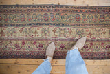 Antique Kermanshah runner with repeating pinwheel florals, scrolled vinery, and navy blue borders.