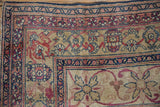 Antique Kermanshah rug corner: pinwheel florals, scrolled vinery, navy, blush, and reconditioned borders.