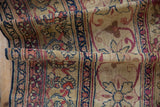 Detailed curvilinear pinwheel floral motifs on an antique Kermanshah runner's aged ivory pile.