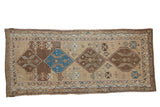Distressed Caucasian runner in sand, brown, and sky blue with geometric diamond medallions.