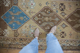 Distressed Caucasian runner showcasing faded sand, chocolate brown, and sky blue geometric patterns.