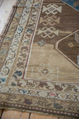 Distressed vintage Caucasian runner detail: sand, brown, blue geometric patterns with even wear.