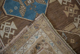 Corner detail of vintage distressed Caucasian runner with geometric sand, brown, and blue patterns, fringe, and woven backing.
