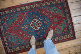 Overhead view of a vintage Persian rug with hexagonal medallions in sapphire blue, cherry red, and green.