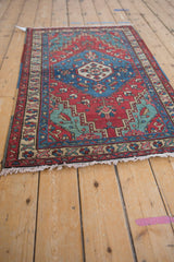 Angled view of a vintage Persian rug, highlighting its colorful geometric pattern and low-pile texture.
