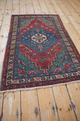 Angled view of a vintage Persian rug showcasing its sapphire blue and cherry red geometric design.