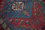 Geometric motifs in sapphire blue and cherry red show the low, even pile of a vintage Persian rug.
