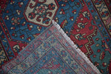 A folded corner reveals the hand-knotted foundation and polychromatic weave of a vintage Persian rug.