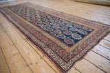View down the length of an antique Kurdish runner highlighting its low pile and boteh design.