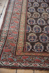 Detailed view of hand-knotted boteh motifs and meandering vine borders on an antique Kurdish rug.