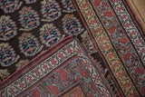 Folded corner of a collectible Kurdish rug shows the boteh pattern and meandering vine border.