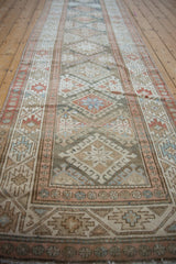 Distressed Persian Hamadan runner detail: hook-and-latch guls, vine border, muted blush and blue.