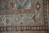 Distressed vintage Hamadan rug runner corner, featuring serrated floral borders and ivory fringe.