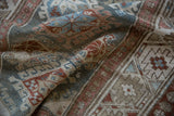 Distressed Hamadan rug texture featuring slate blue, red, and ivory geometric guls and motifs.