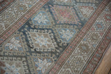 Close-up of distressed Hamadan runner's hook and latch guls and checkered blush border.
