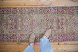 A view down a distressed Yezd runner showing time-softened magenta and olive floral motifs.