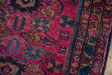Detail of a vintage Lilihan rug with raspberry red field, hidden animal motifs, and a rich blue border.