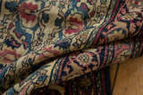 Intricate vinery, stylized blossoms, and cochineal red abrash on a folded antique Kermanshah rug.
