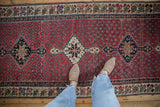 A vintage Kurdish runner with inverted coloration stepped medallions on a madder red seed motif field.