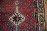 Vintage Kurdish runner's ivory medallion, red field with seed motifs, and geometric border.