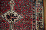 Close-up of a vintage Kurdish rug's stepped medallion, seed motif, and multi-layered border.