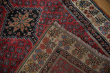 The hand-knotted weave and rich red pile of a vintage Kurdish rug's corner.