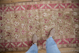 A standing view of a distressed vintage Karabagh runner, highlighting its soft wheat and fuchsia boteh pattern.