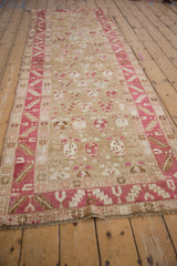 Perspective view of a distressed Karabagh runner's decorative boteh pattern and serrated leaf border.