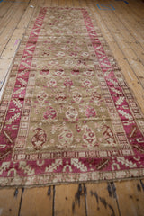 Lengthwise view of a distressed Karabagh runner with raspberry botehs on a wheat field.