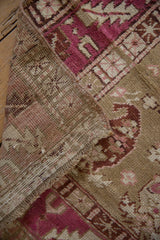 Folded corner of a distressed Karabagh runner showing the raspberry pile and hand-knotted foundation.