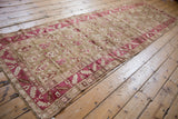 Long vintage Karabagh runner at an angle, with raspberry botehs and a sharp serrated leaf border.