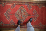 The central hexagonal medallion and ram's horn finials on a vintage Serab runner's abrashed red field.