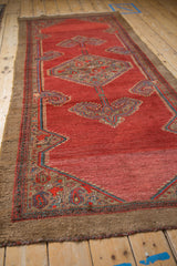 Angled view along a vintage Serab runner, showing the wide camel border against the abrashed red pile.