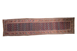 Vintage Kurdish runner featuring colorful staggered plant motifs and a navy ground, 3'5