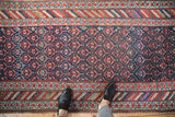 Vintage hand-knotted Kurdish runner with geometric plant motifs and rainbow-hued striped borders.