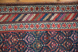 Hand-knotted vintage Kurdish runner featuring red floral border and vibrant diagonal stripes.
