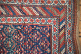Hand-knotted vintage Kurdish rug: navy field, red-and-ivory floral border, textured selvage.
