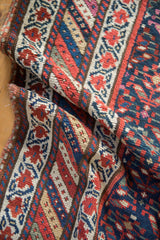Textured hand-knotted pile with navy, red, and beige stylized plant motifs and selvage.