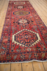 Vintage Heriz runner with repeating serrated medallions, cherry red field, and sapphire blue patterns.