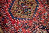 Close-up of vintage Heriz runner, dusty gold serrated medallion, cherry red field, sapphire blue geometric motifs.