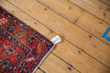 Corner of a vintage Heriz runner, showcasing cherry red, sapphire blue pile, and intact selvage.