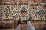 Vintage Northwest Persian runner's geometric hook and latch medallions in navy and rust on sand.