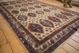 Angled perspective of a Northwest Persian carpet showing its repeating geometric panel design in red and blue.