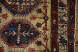 Visible knot heads and geometric boteh border on a vintage Northwest Persian carpet corner.