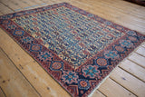 Angled perspective of an antique Afshar rug's floral lattice design in saffron, navy, and red.