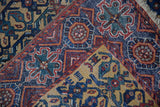 Detailed floral lattice motifs in navy, red, and saffron on a hand-knotted antique Afshar rug.
